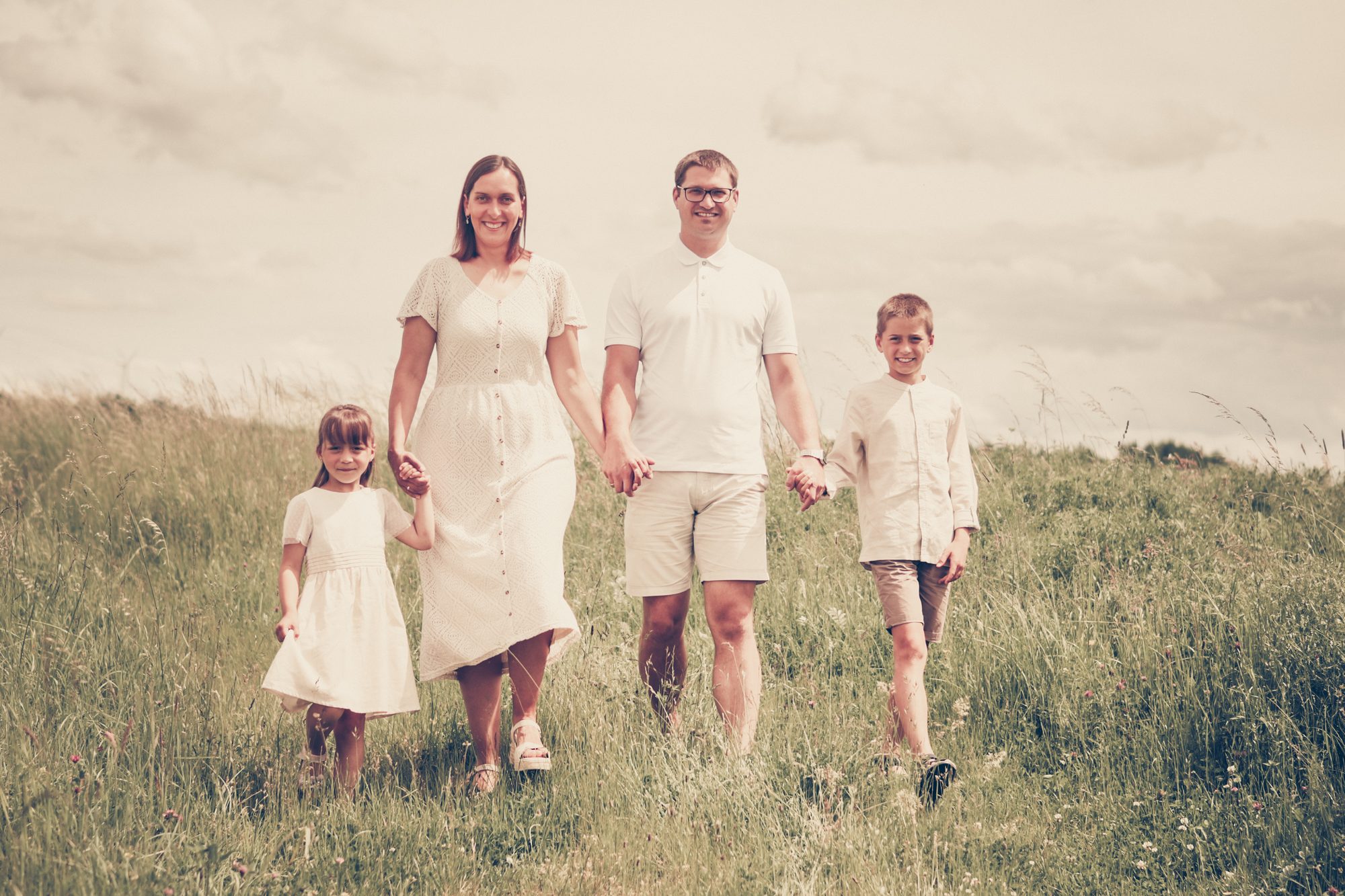 Familienshooting outdoor in Duingen: Familie geht Hand in Hand durch die Wiese, Vintage-Look