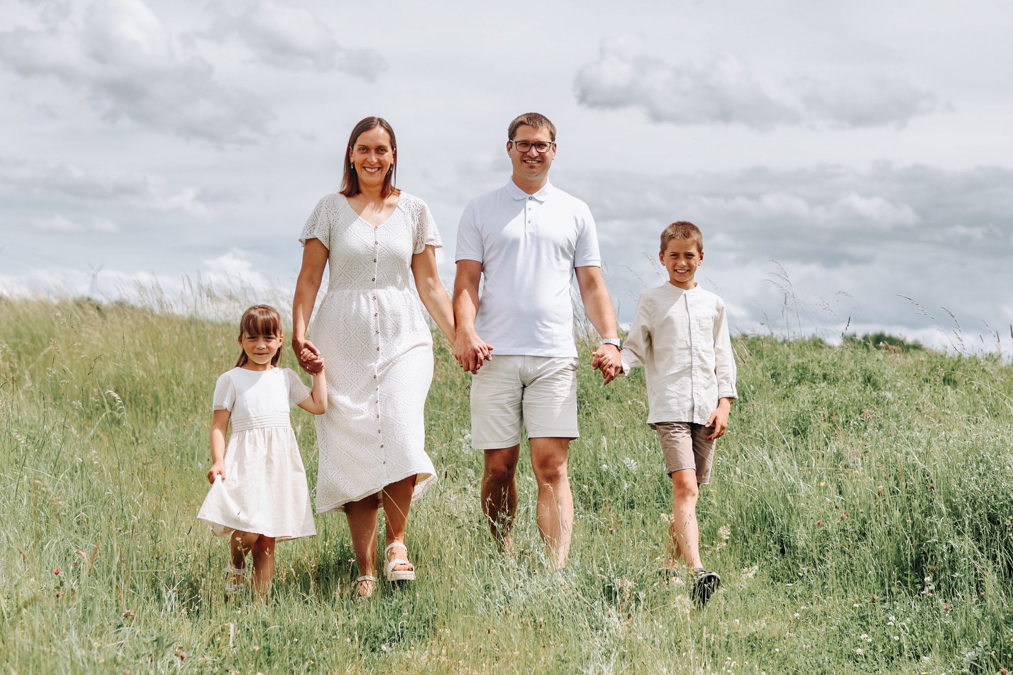 Familienshooting outdoor in Duingen: Familie geht Hand in Hand durch die Wiese