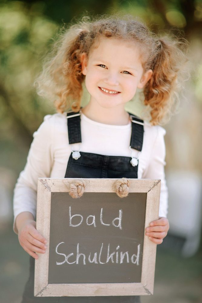 Vorschulkind mit Kreidetafel „bald Schulkind“ beim Fototag